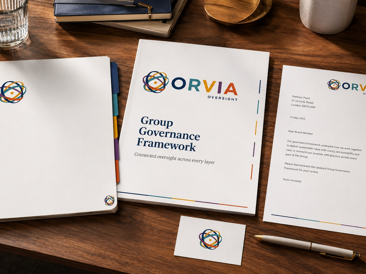 A Group Governance Framework binder and covering letter on a walnut desk beside notebooks and a pen, presented in ORVIA Oversight branded stationery.